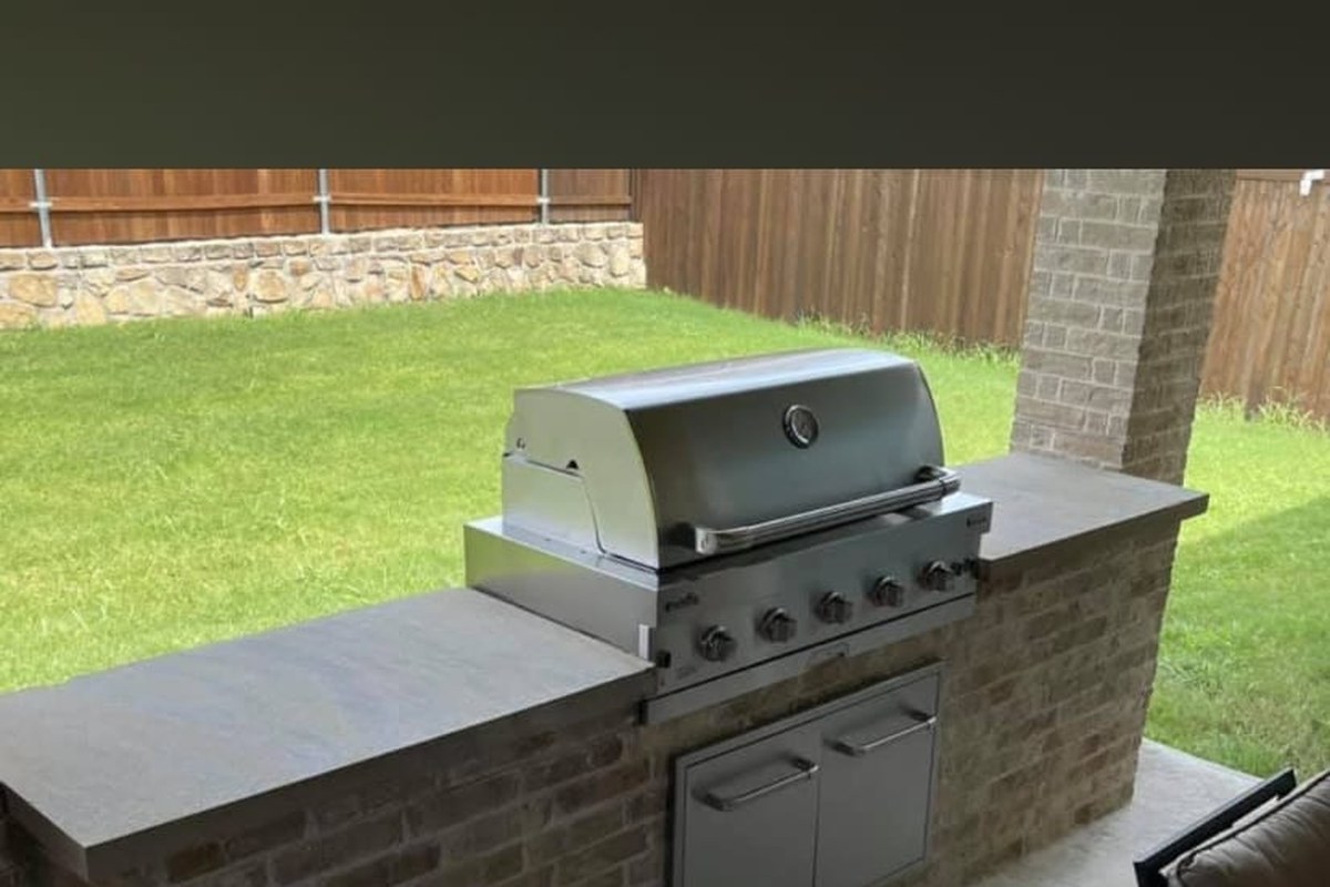 Cocina exterior con parrilla empotrada y barra de ladrillo